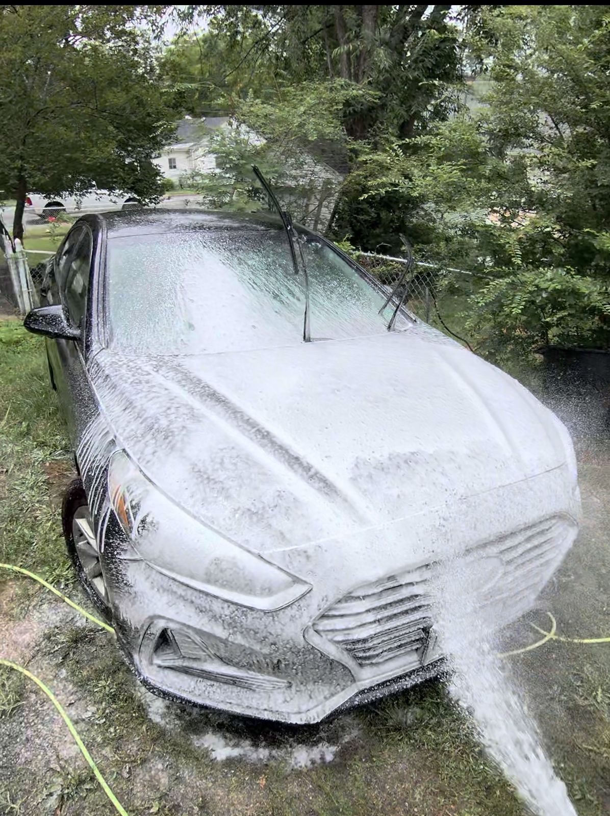 Sedan covered in thick foam during a mobile hand wash
