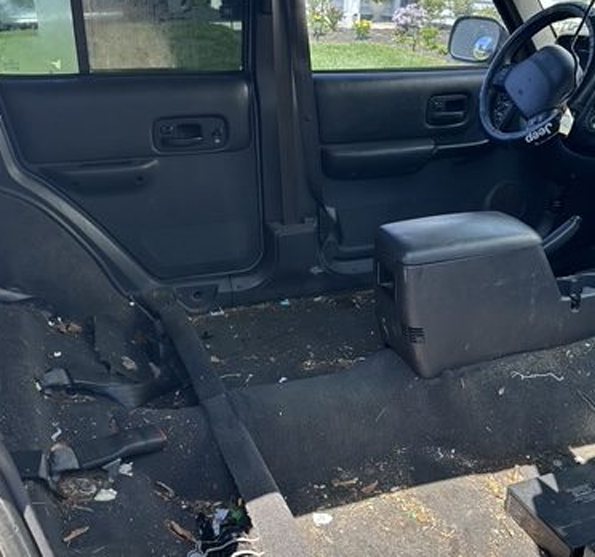 The same Jeep interior with seats removed and debris covering the floor before detailing