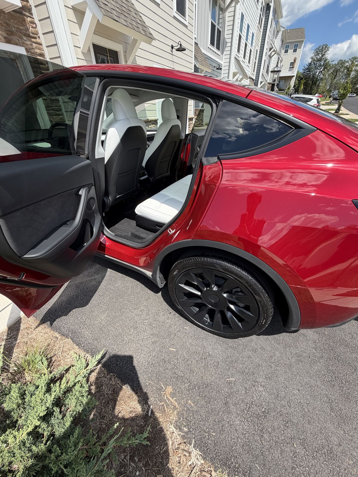 Red Tesla Model Y with rear door open showing clean white rear seats